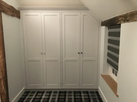 Fitted wardrobe in a Dedham period cottage with shaker doors scribed to the angled ceiling