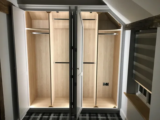 Lit interior of the Dedham fitted wardrobe showing hanging rails and oak-effect lining