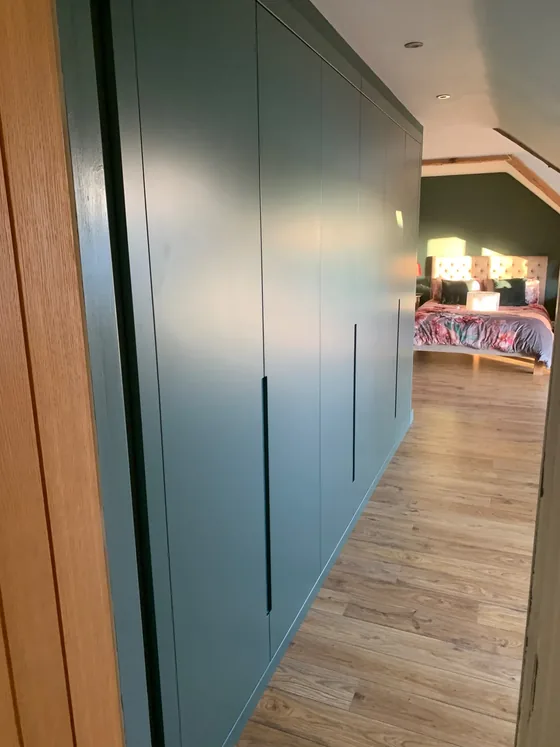 Floor to ceiling fitted wardrobe in Manningtree with handleless doors sprayed to match the wall