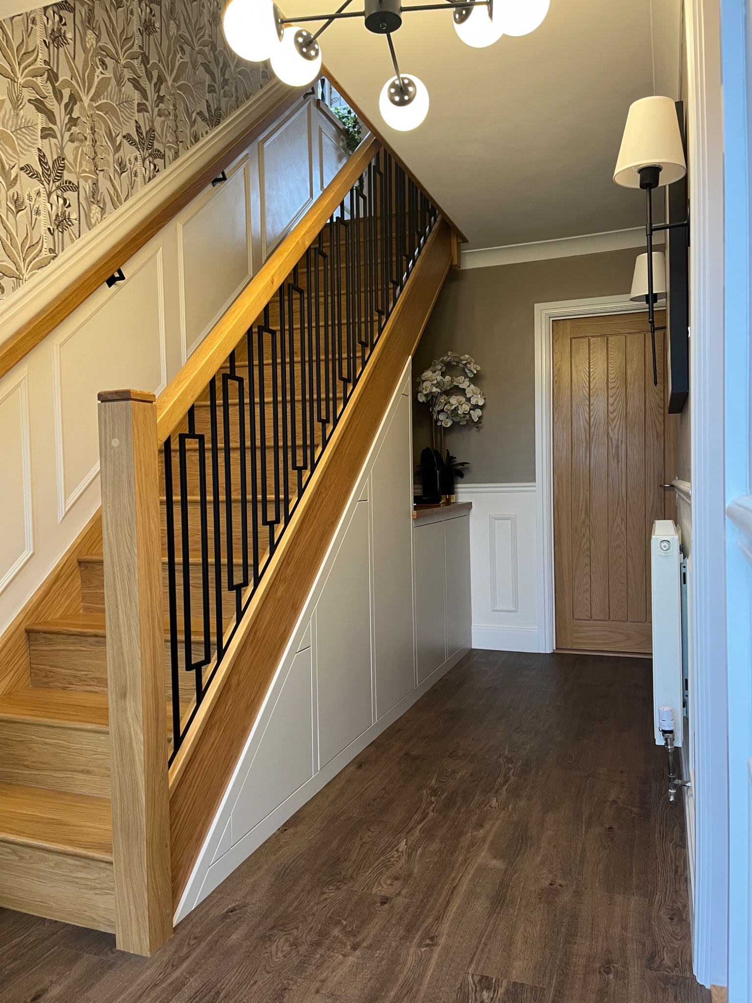 Finished hallway in Harwich with a solid oak staircase, black metal balustrade and wall panelling