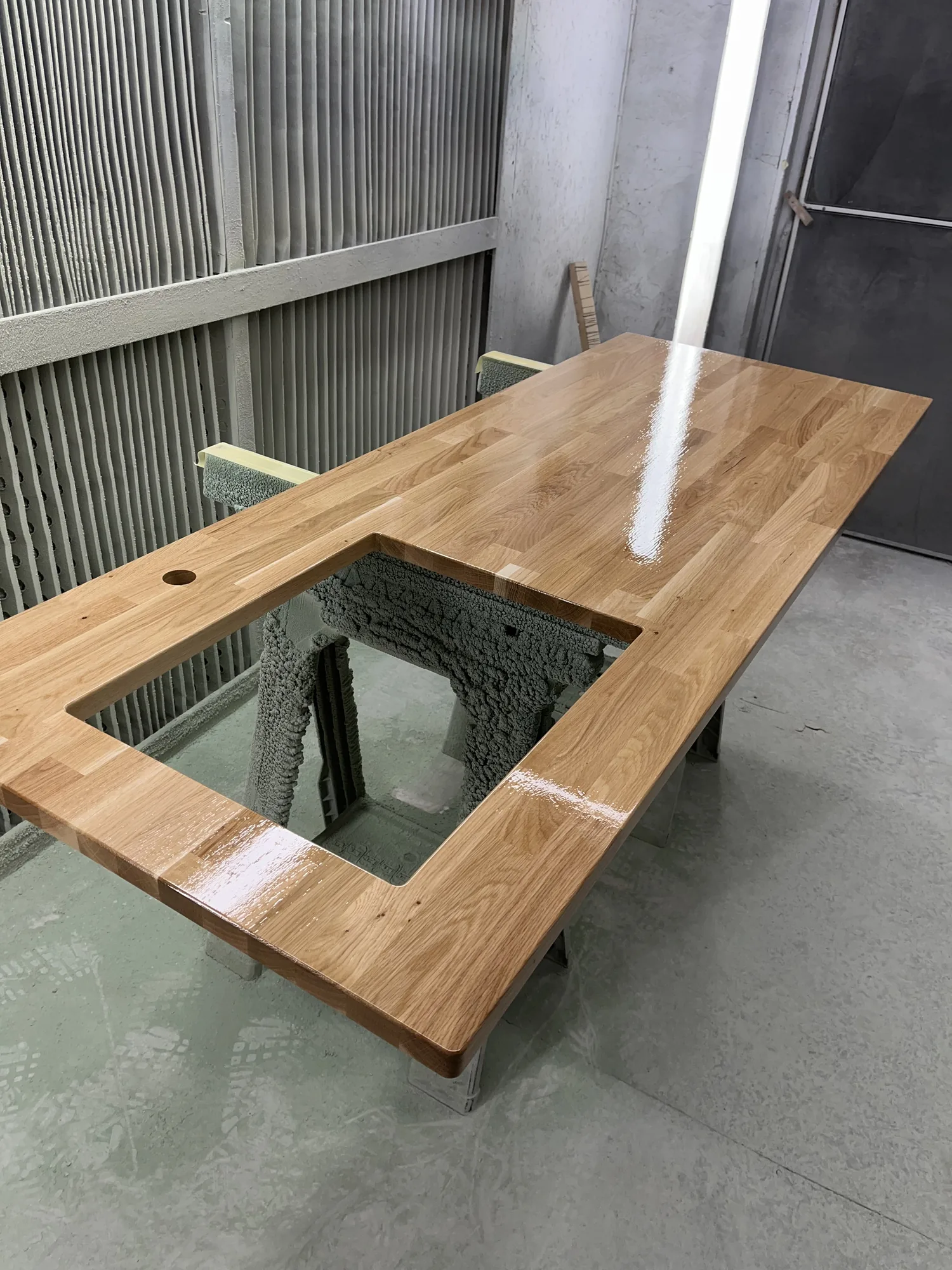 Oak dining top being spray-finished with clear lacquer in the workshop