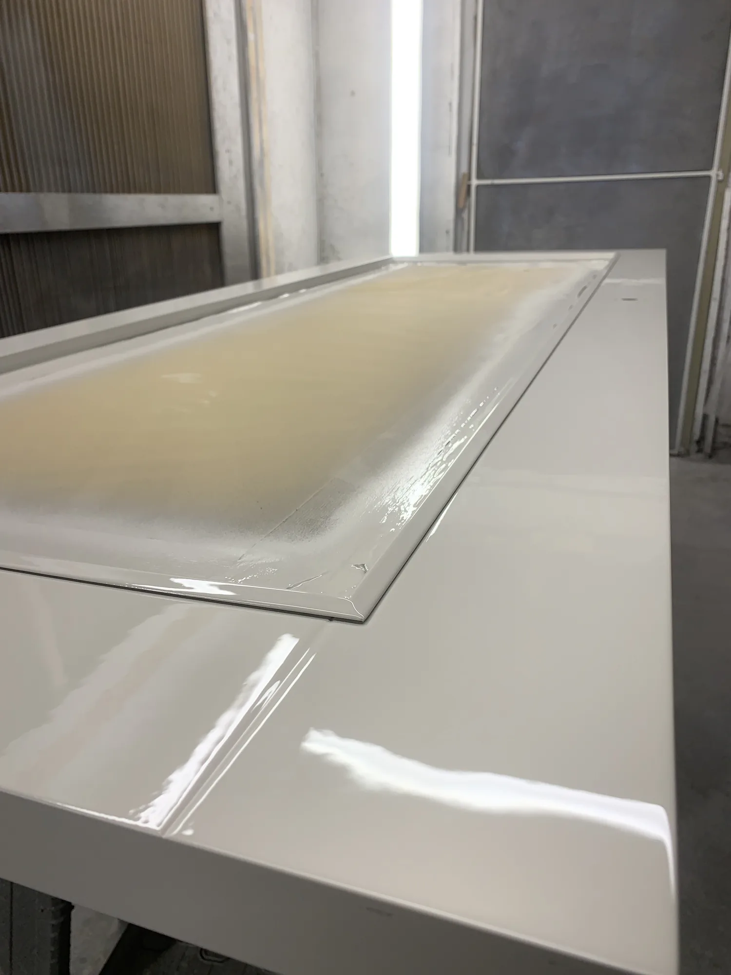 Workshop spray booth mid-application on solid oak